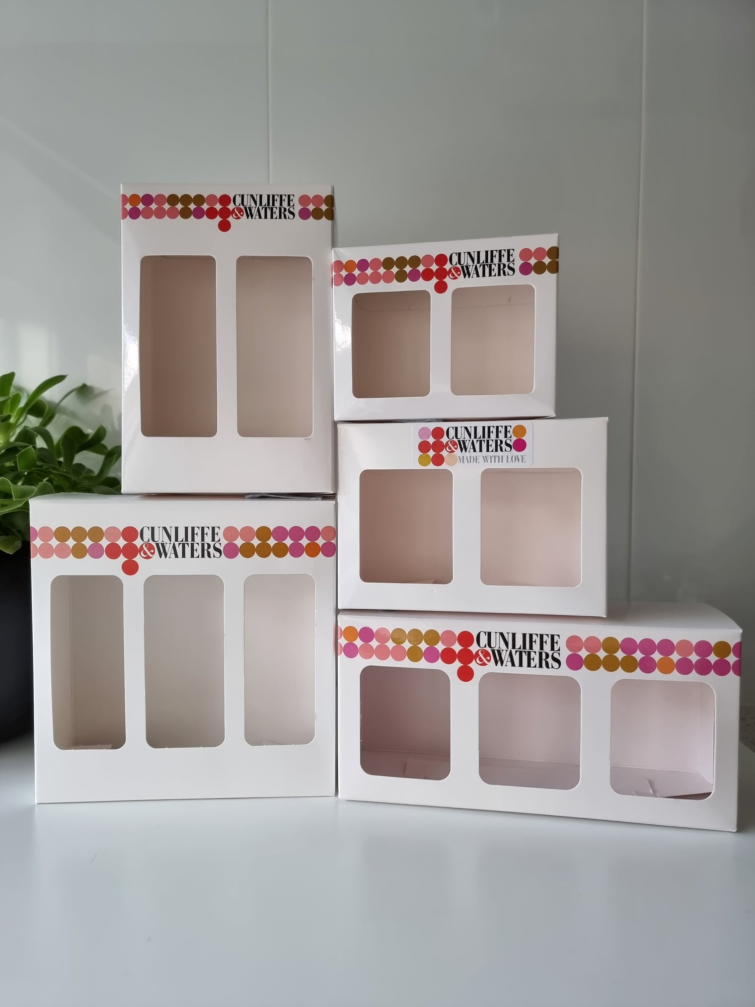 A set of white Cunliffe & Waters gift boxes with multicolored decorative elements on the lids.